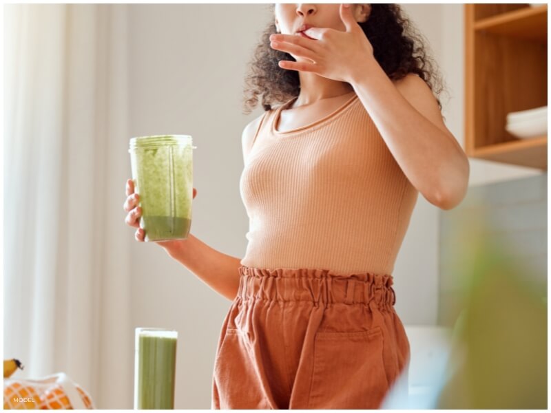 A focused young woman in athletic wear holding a protein shake, symbolizing commitment to health and wellness, featured on a weight loss surgery blog advocating a holistic approach to overall health improvement