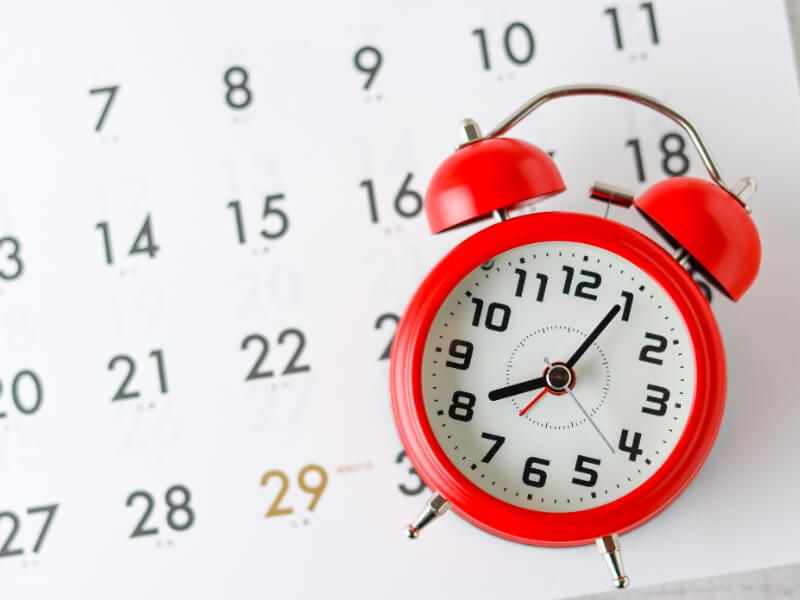a photo of a clock and calendar emphasizing that timing is everything when planning breast augmentation surgery